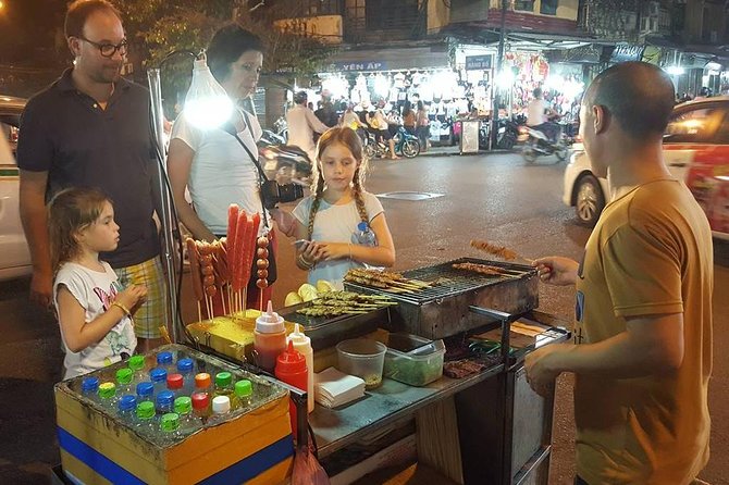 A lit food stall serving a queue after dark